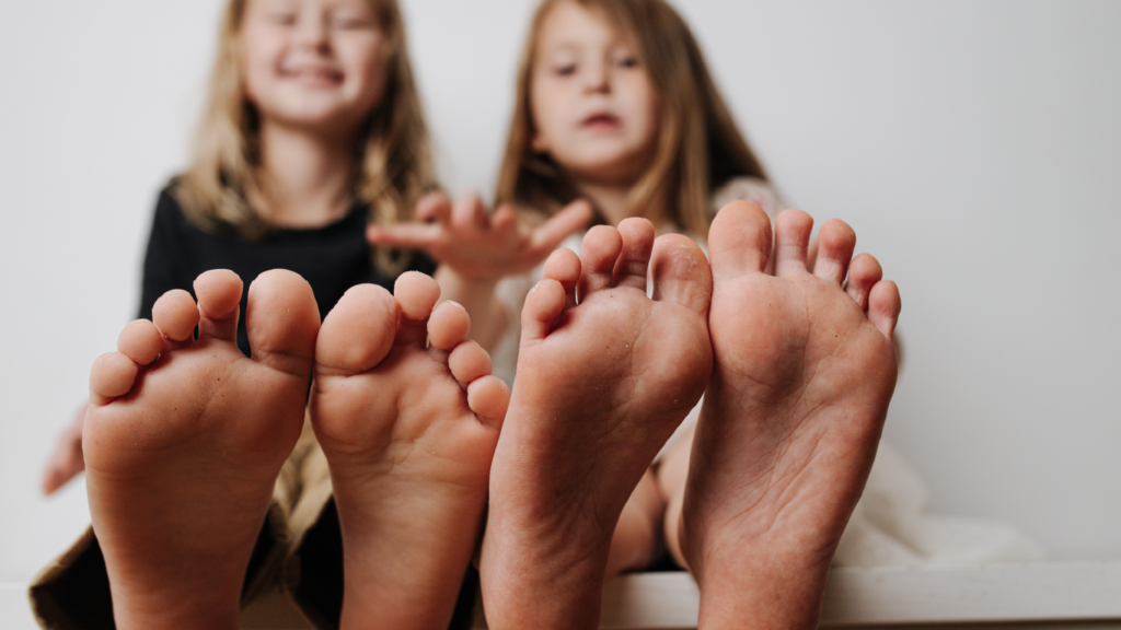 Twee kinderen zitten met hun blote voeten naar voren