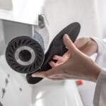 Steunzolen specialist schuurt en vormt een op maat gemaakte steunzool voor een patiënt.