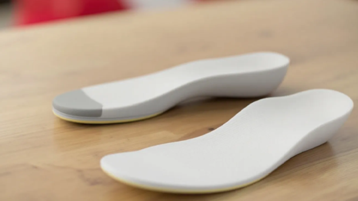 Een paar witte podologische zolen op een tafel, ontworpen voor optimaal voetcomfort en ondersteuning