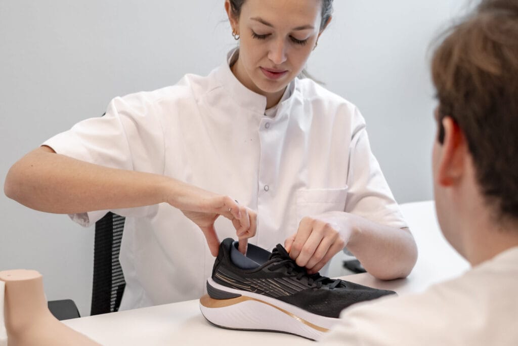 Sportzolen op maat 1 Podoloog Margaux Verstraete bespreekt hardloopschoenen met een sporter