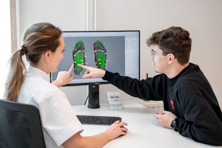 Margaux Verstraete bespreekt de 3D-voetscan met een patiënt aan de computer