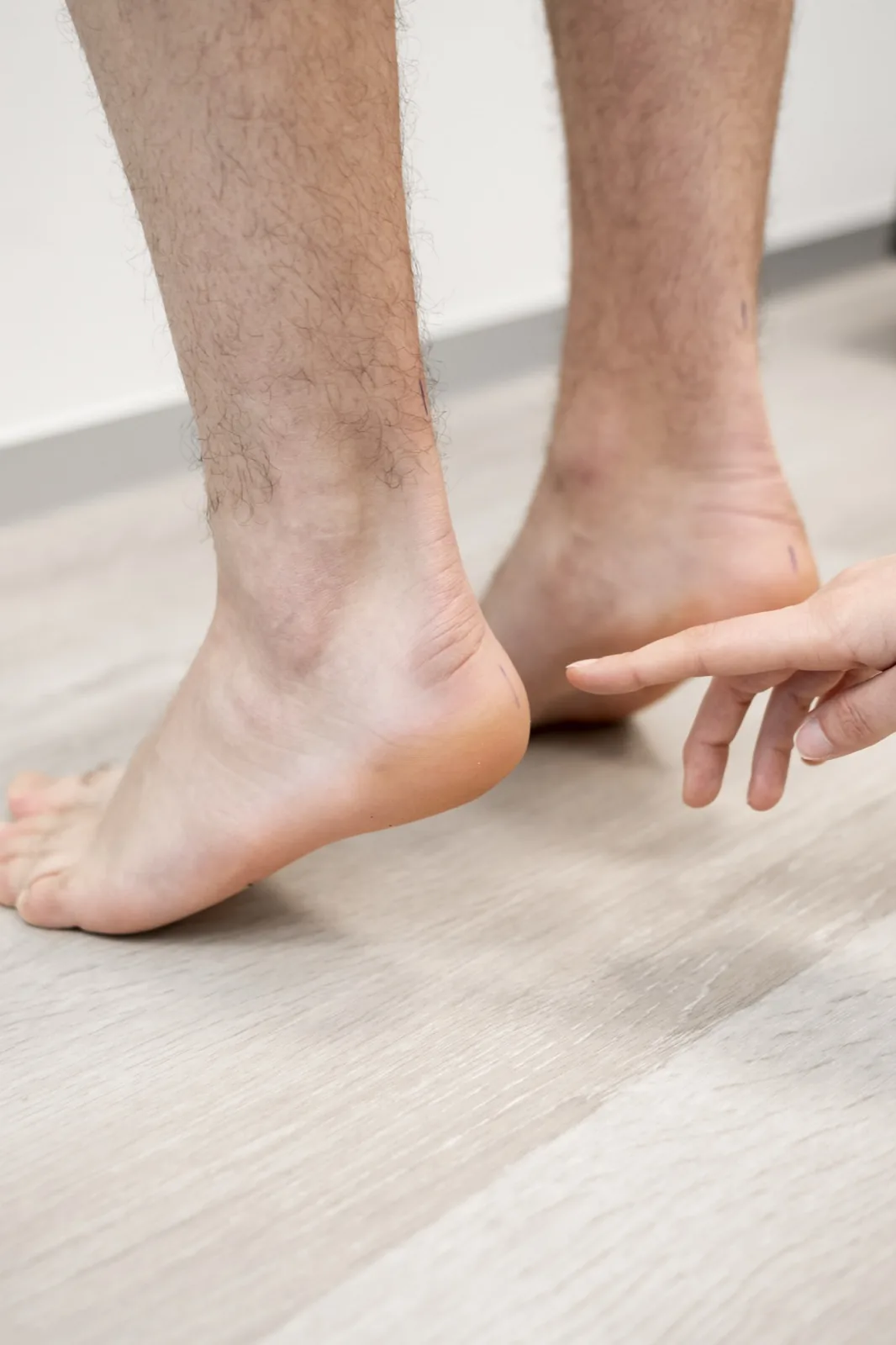 Podoloog voelt aan de onderkant van de hiel tijdens een onderzoek naar hielspoor