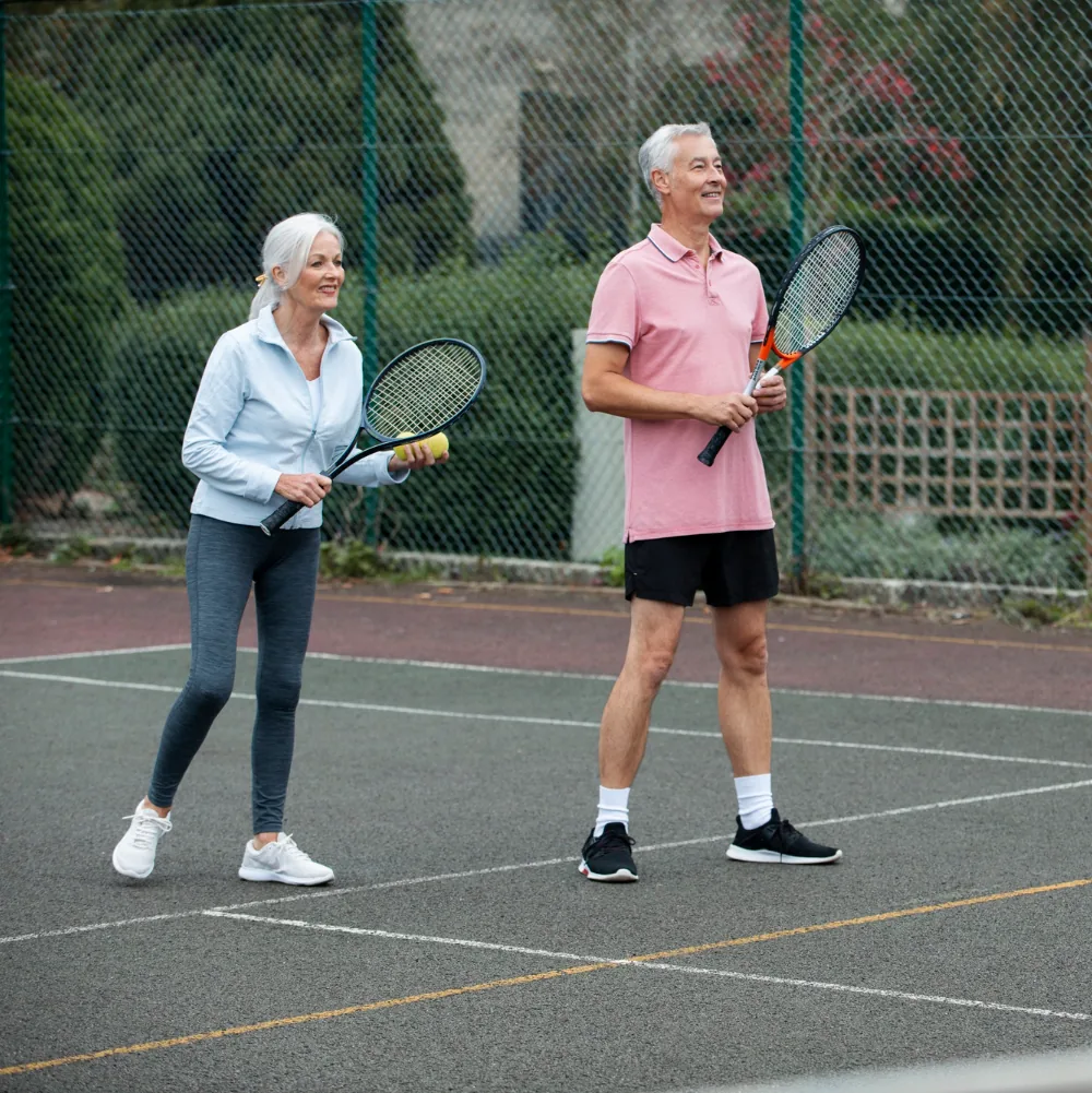 Een oudere man en vrouw spelen lawn tennis, met focus op volwassenen.
