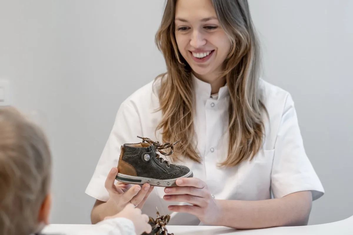 Margaux Verstraete houdt een kinderschoen omhoog aan haar bureau
